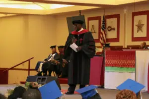 A man in a cap and gown is speaking at a graduation ceremony.