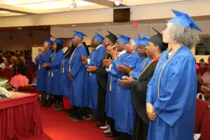 A group of people in blue graduation gowns clapping.