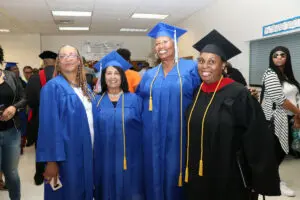 Four women in blue graduation gowns posing for a photo.