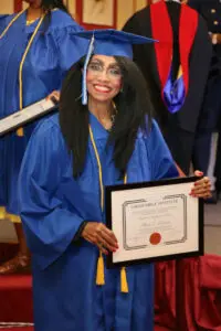 A woman in a blue gown holding a diploma.
