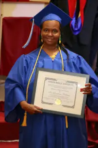 A woman in a graduation gown holding a certificate.