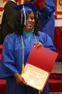 A woman in a blue graduation gown holding a certificate.