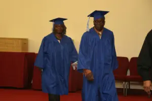 A man and a woman in blue graduation gowns.