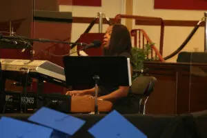 A woman playing a keyboard in front of a microphone.