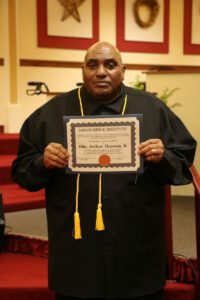A man holding a certificate in front of a church.