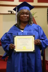 A woman in a blue robe holding a certificate.