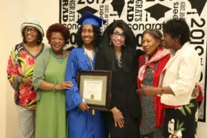 A group of women posing for a photo with a graduation certificate.