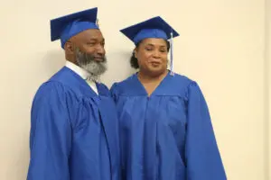 Two people in blue graduation gowns standing next to each other.