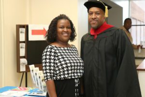 A man and woman posing for a photo in a graduation gown.