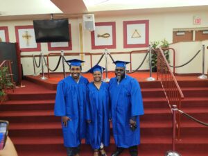 Three people in blue graduation gowns posing for a photo.
