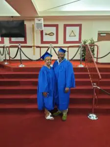 Two people posing for a picture in graduation gowns.