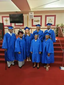 A group of people in blue graduation gowns posing for a photo.